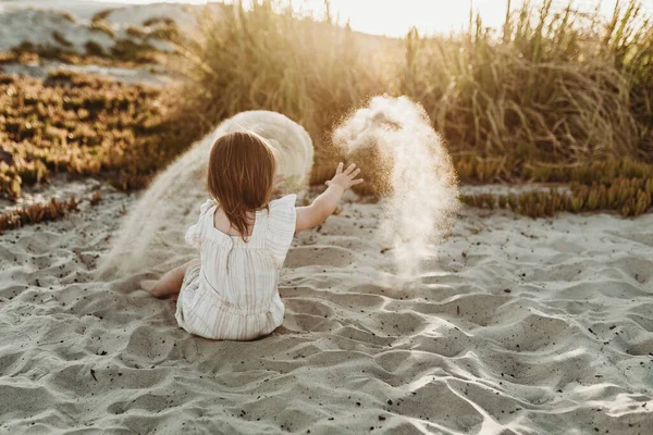 若い幼児の女の子は日没時に砂の上で遊ぶ — ストック写真