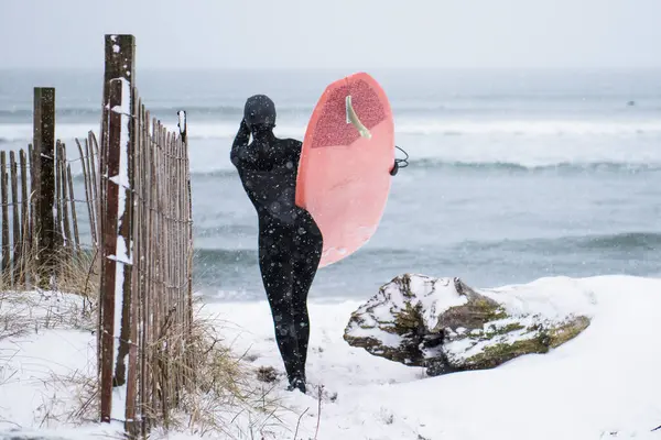 ニューイングランドの冬の時間にビーチでサーフボードを持つ女性 — ストック写真
