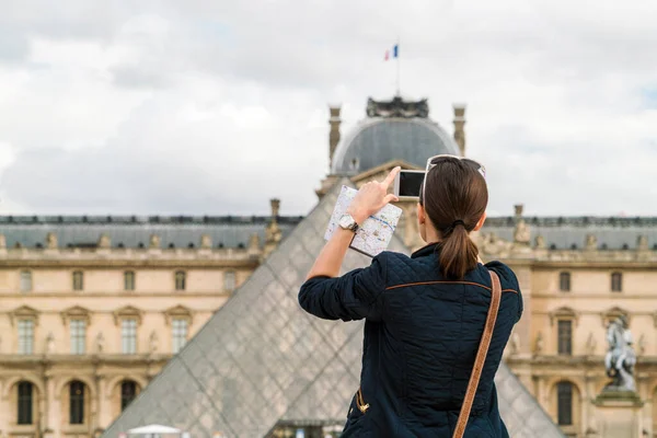携帯電話でパリのルーブル美術館の写真を撮る女性 — ストック写真