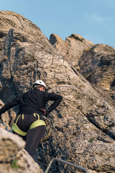 ヘルメットとハーネスを持つ登山女性 後ろだ 登山を続ける前に休憩 山の中のフェラタを経由して — ストック写真