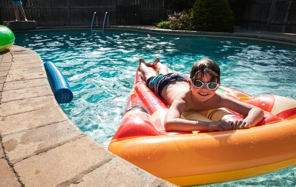 小男孩带着护目镜在后院里的游泳池里玩着比萨饼 — 图库照片