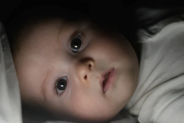 数ヶ月の赤ちゃんは シートの下の光を見て 選択的な焦点を当てて — ストック写真