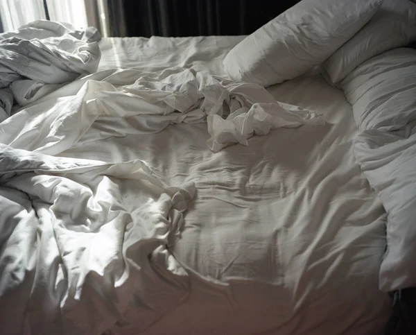 Несделанная спальная кровать под утренним солнцем — стоковое фото