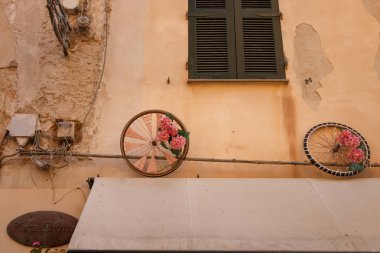 Eski evde Alghero İtalyan Sardunya Adası üzerinde eski püskü bir faade, iki renkli tekerlek ile süslüdür.