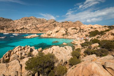 Caprera, İtalya - 8 Eylül 2017: Beach life Spiaggia Cala Coticcio taşlara Caprera İtalyan Adası üzerinde oturan kişi ile