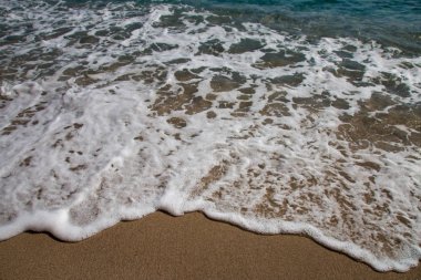 Deniz köpüğü ve yumuşak dalga İtalyan Sardunya Adası bir kum Plajı üzerinde