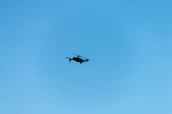 A drone flying in the air in front a blue sky