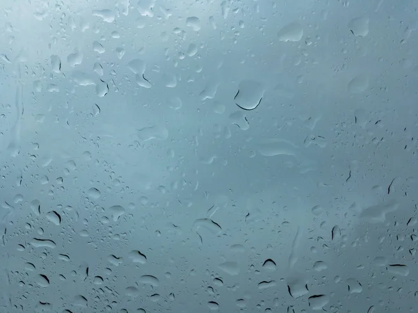 Huge drops of rain on glass, rain drops on clear glass roof of a car