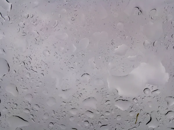 Huge drops of rain on glass, rain drops on clear glass roof of a car
