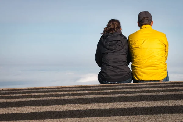 Couple sitting on a crosswalk above the clouds