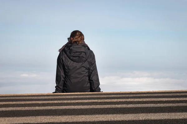 Woman sitting on a crosswalk above the clouds