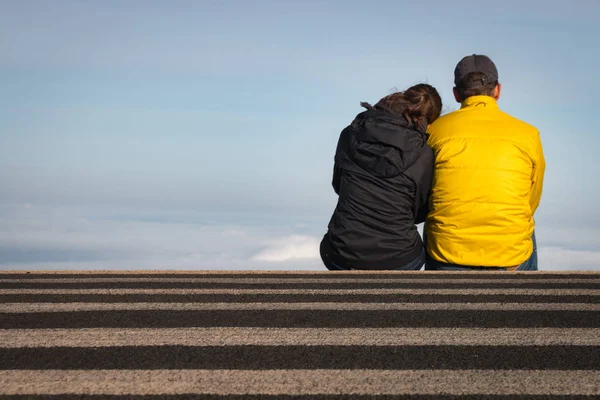 Couple sitting on a crosswalk above the clouds