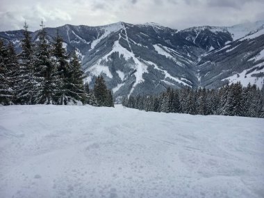 Avusturya Alpleri 'ndeki Saalbach-Hinterglemm kayak bölgesinde Viehofen' in kayak rotasındaki dağların manzarası bulutlu gökyüzüne karşı