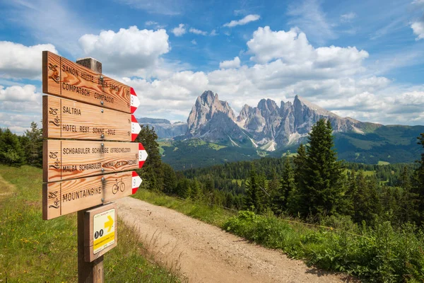 Yazın Alpe di Siusi - Seiser Alm ve Sassolungo - Langkofel dağ grubu arasındaki yürüyüş yolu boyunca işaret direği ve manzara.