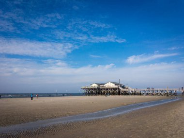 Sankt Peter-Ording, Almanya - 5 Ekim 2018: Kuzey sahili ve sonbaharda mavi gökyüzüne karşı alçak gelgit sırasında stilt evi.