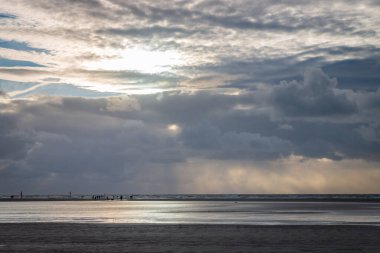 Sankt Peter-Ording, Almanya 'da dramatik gökyüzüne karşı gün batımında alçak deniz plajının panoramik görüntüsü