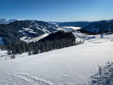 Avusturya 'daki Saalbach Hinterglemm kayak bölgesindeki karlı dağların panoramik manzarası mavi gökyüzüne karşı.