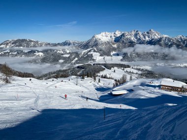Lofer Dağları (sağda) ve Fieberbrunn 'un kayak yamaçlarında mavi gökyüzüne karşı uzanan kar manzarası