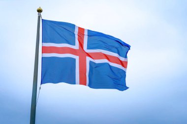 İzlanda 'nın mavi, kırmızı ve beyaz ulusal bayrağı bulutlu bir arka planda dalgaların ortasında yakalandı.