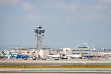 Los Angeles, Kaliforniya, ABD - 19 Nisan 2024: Los Angeles Interanationl Havaalanı LAX kontrol kulesi ve tema binası bulutlu gökyüzüne karşı pistlerde görüldü