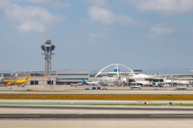 Los Angeles, Kaliforniya, ABD - 19 Nisan 2024: Los Angeles Interanationl Havaalanı LAX kontrol kulesi ve tema binası bulutlu gökyüzüne karşı pistlerde görüldü