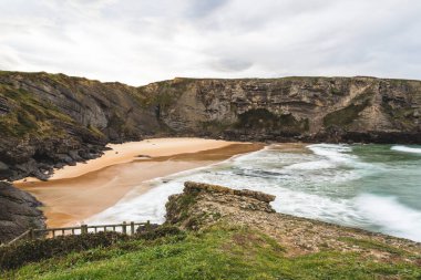 İspanya, Cantabria 'da bulutlu bir günde dalgalı Antuerta plajı