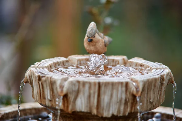 figurine of a bird at a decorative summer fountain, water