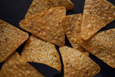 Siyah zeminde baharatlı tortilla cipslerinin üst görüntüsü
