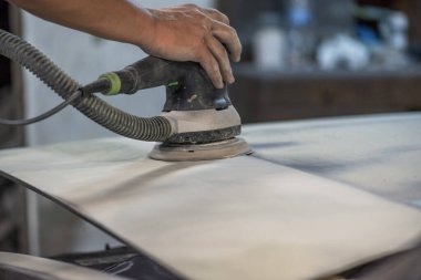 Araba tamirhanesinde araba cilalayan bir adamın elinde öğütücü..