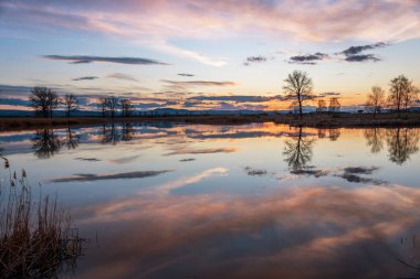 Sakin göl üzerinde gün batımı, kışın suda gökyüzü yansıması..