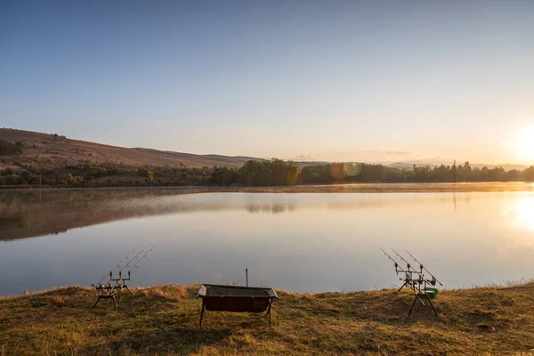 鯉の一口指標とリールを持つ鯉釣りロッドは 湖の川の近くのロッドポッドに設定します 日の出時の釣り — ストック写真