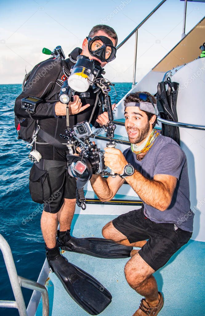 crew member on a scuba dive vessel checking pictures from his buddy