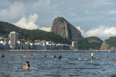Copacabana Sahili 'ne güzel bir manzara. Arkasında Sugar Loaf dağı ve Stand Up Paddle tahtasındaki insanlar, Rio de Janeiro, Brezilya