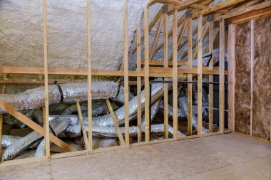 Çatısı ahşap kirişlerle döşenmiş boru ısıtma sistemi yapım aşamasındaki bir evin tavan arası.