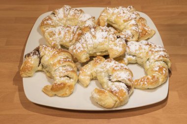 Çikolatayla doldurulmuş ayçöreği seramik tabağın tepesinde şeker bardağıyla.