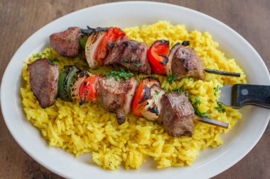 Ahşap masada ızgara tavuk şiş kebap ve pilav.