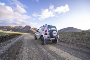 Dağ tepelerine doğru giden toprak yolda küçük 4x4 'ün arka görüntüsü