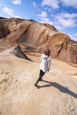 Kum tepeciğinde yokuş aşağı yürüyen genç kadının manzarası