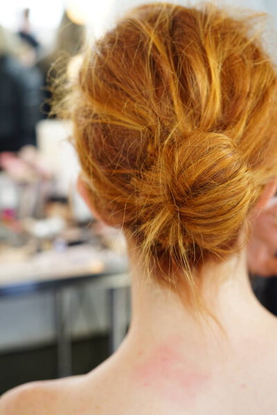 Молодая женщина сидит для волос и макияжа с грязной прической булочки