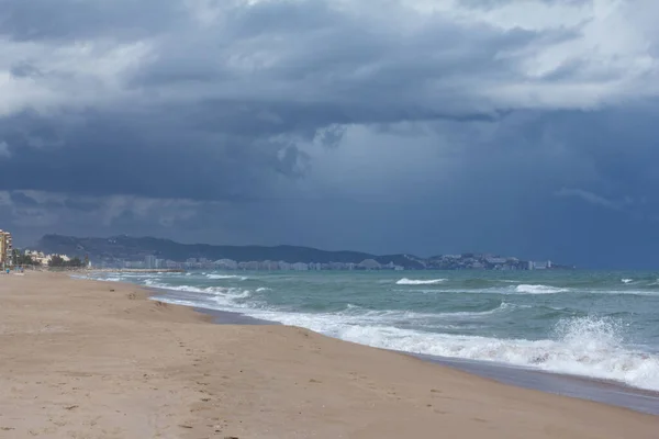 街のスカイラインと砂浜の上の風景青い嵐の雲 — ストック写真