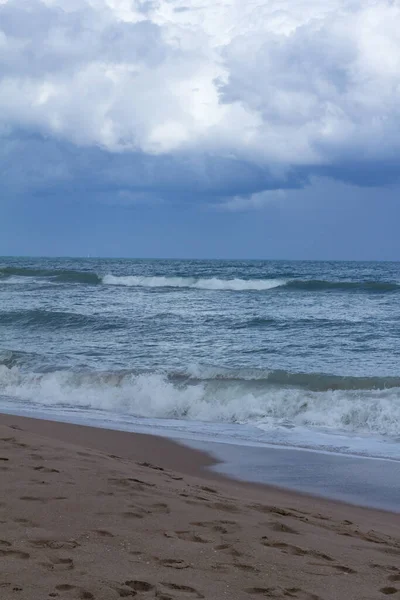 濃い青の水で砂浜の上に灰色の嵐の雲 — ストック写真