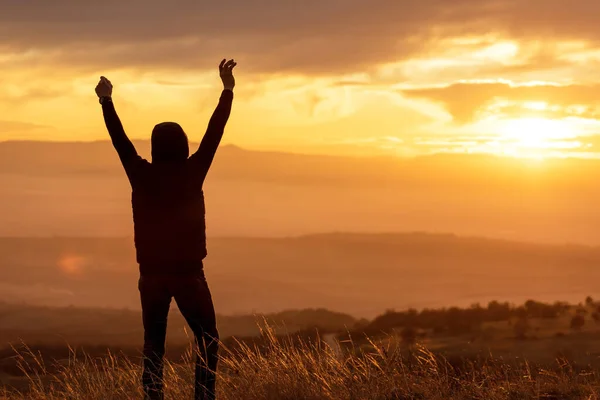 The man stands arms up on the mountain. thanks to God.