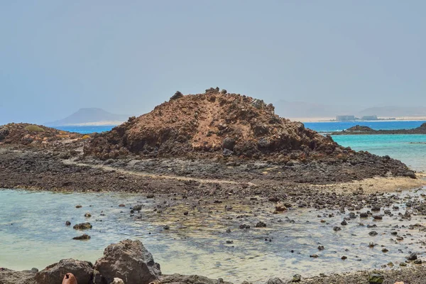 Nice little island with turquoise water in the small port of Isla de Lobos with corralejo dunes of great beaches in the background in Canary Islands, Spain