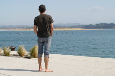 Santander kıyısında yürüyen bir adam var. Dağın doğusunda ve Dunas del Puntal y Estuario del Miera arka planda.