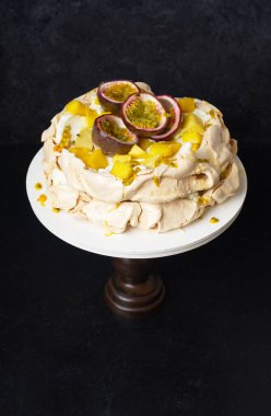 Tutku meyveli Pavlova keki, mango, limon ve muz kreması koyu arkaplanda.