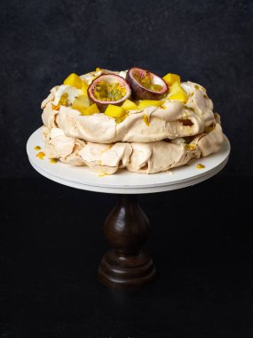 Tutku meyveli Pavlova keki, mango, limon ve muz kreması koyu arkaplanda.