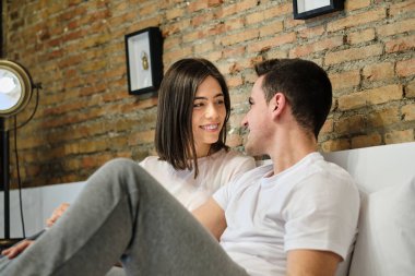 Romantik genç çift yatakta dinlenirken birbirlerine bakıyorlar.