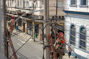 COVID-19 yüzünden maskeler kullanarak elektrik şebekesi kablolarını tamir eden adamlar.