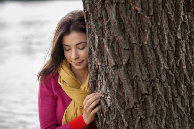 Güzel esmer kız sonbaharda nehir kenarında poz veriyor. 