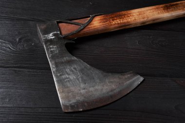 Siyah tahta arka planda gerçek bir İskandinav baltası, durgun hayat, viking baltası, yanmış çelik